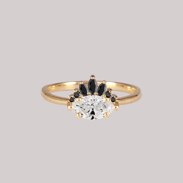 Contemporary take on a traditional marquise diamond ring featuring an East-West marquise brilliant cut diamond. The centre stone is surrounded with a diamond crown of black marquise and round brilliant diamonds. Made in solid 14k or 18K yellow gold.