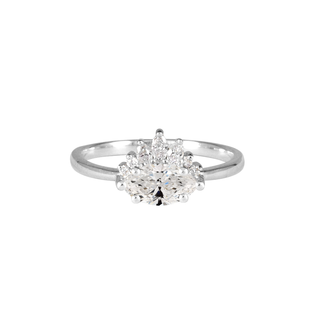 Contemporary take on a traditional marquise diamond ring features an East-West marquise diamond. The centre stone is surrounded with a diamond crown of marquise and round brilliant diamonds. Made in solid 14k or 18K white gold.