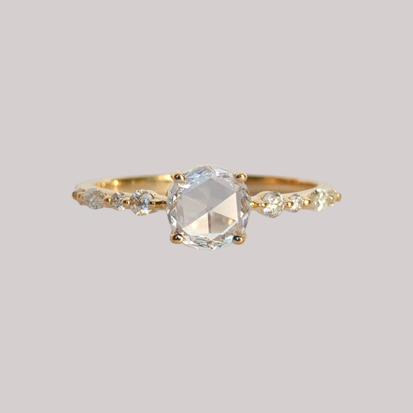 A twist on a classic solitaire engagement ring, featuring a round rose cut diamond, set with four prongs. The main diamond sits on maquise and round brilliant cut diamond band. Made in 14k or 18k yellow gold. 